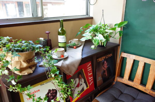 鞆町カフェー454の店内で、観葉植物とレコードジャケット、カップが並べられたディスプレイの写真
